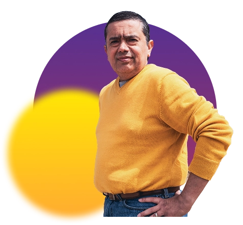 Man in a yellow sweater standing with one hand on his hip.