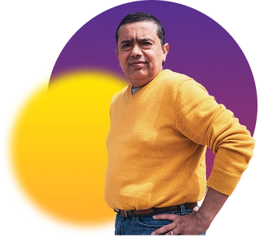 Man in a yellow sweater standing with one hand on his hip.
